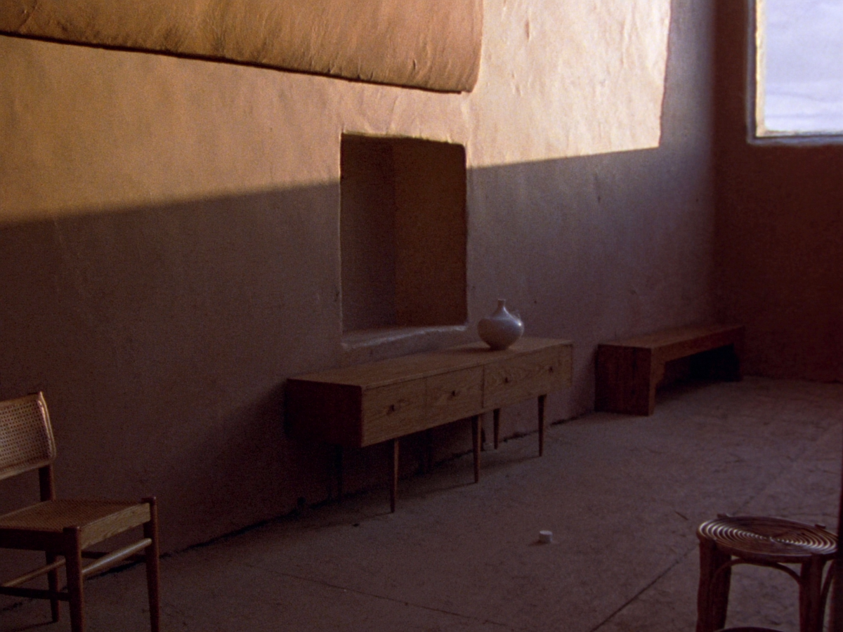 A solid oak sideboard, cane-backed chair and acacia bench in a warm clay-plaster room